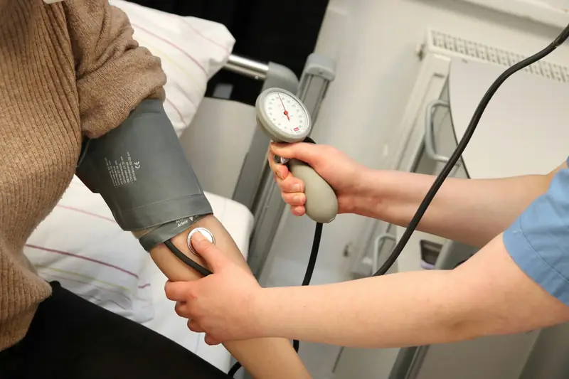 Eine Fachperson misst einer Patientin am Arm den Blutdruck.