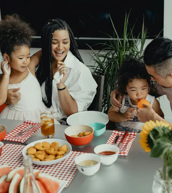 Eine Familie sitzt beim Essen an einem gedeckten Tisch.