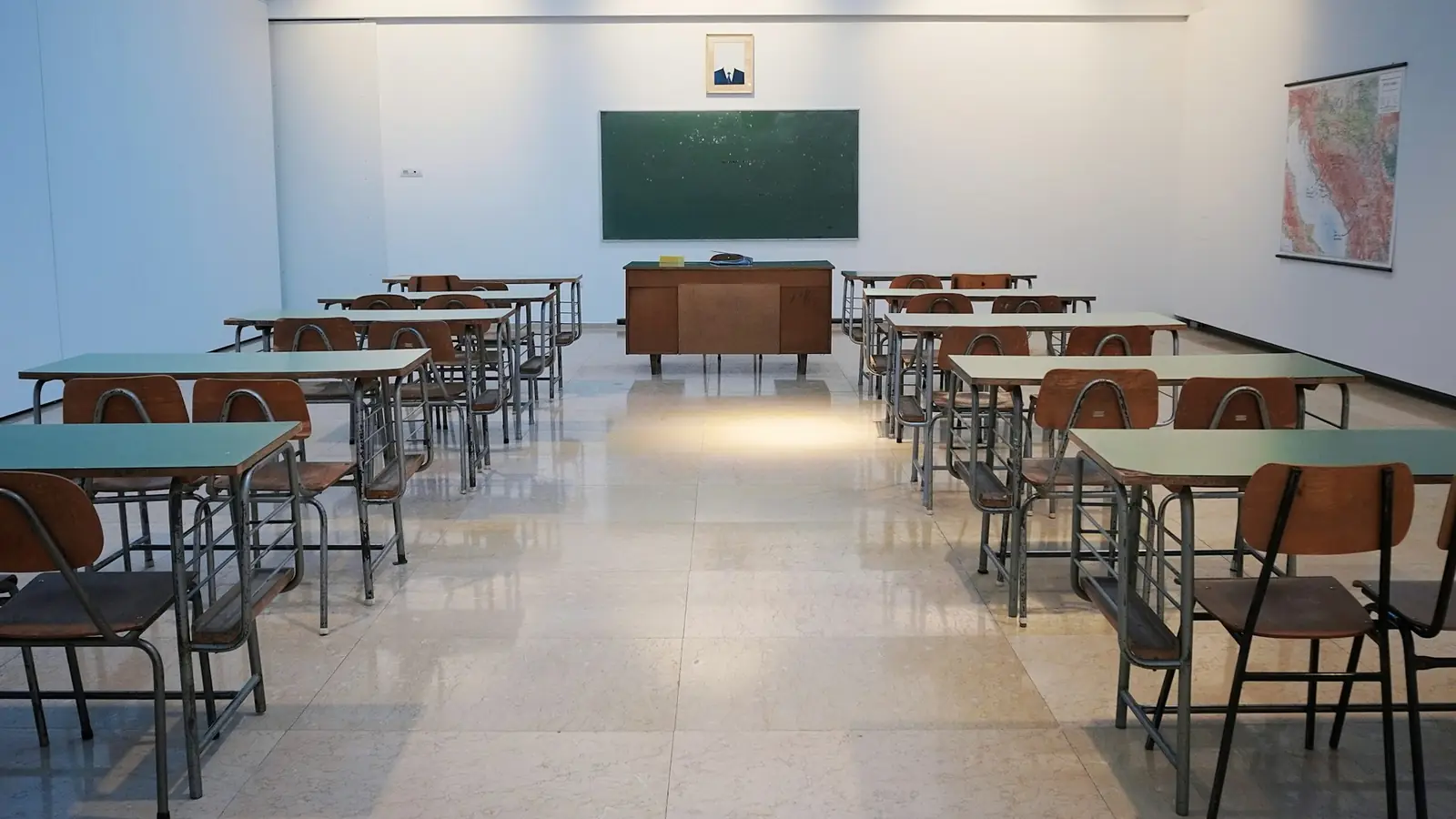 Ein leeres, helles Klassenzimmer mit Pulten und einer grünen Wandtafel.
