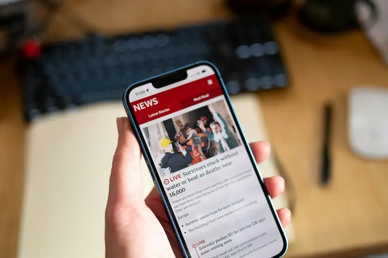Eine Hand hält ein Telefon mit einer Nachrichtenseite.